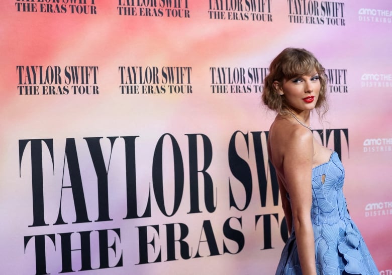 A woman in a blue dress turns her head to pose for cameras. 