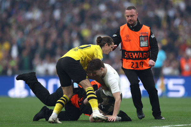 Marcel Sabitzer of Borussia Dortmund assists members of security as they stop a pitch invader.