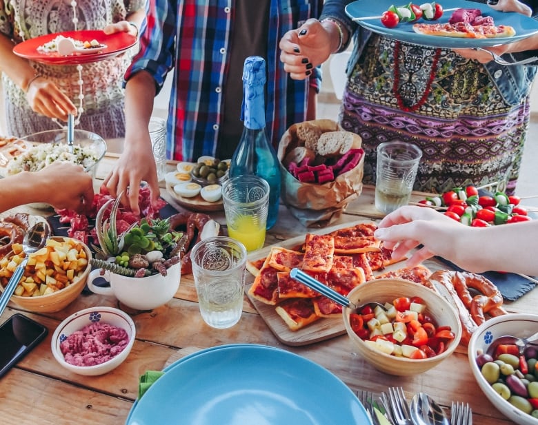 People holding plates to get food and drinks on a table