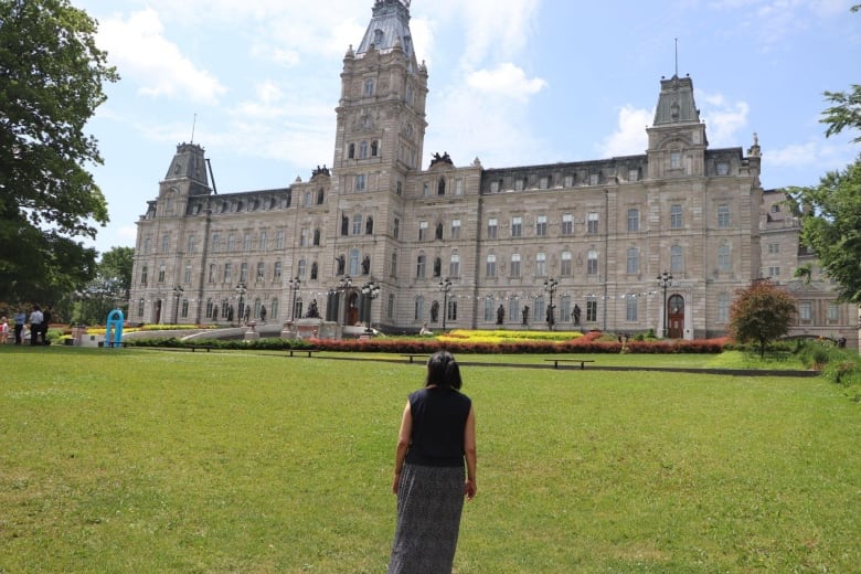 A woman stands with her back to the camera. She is facing the national assembly building in Quebec City.