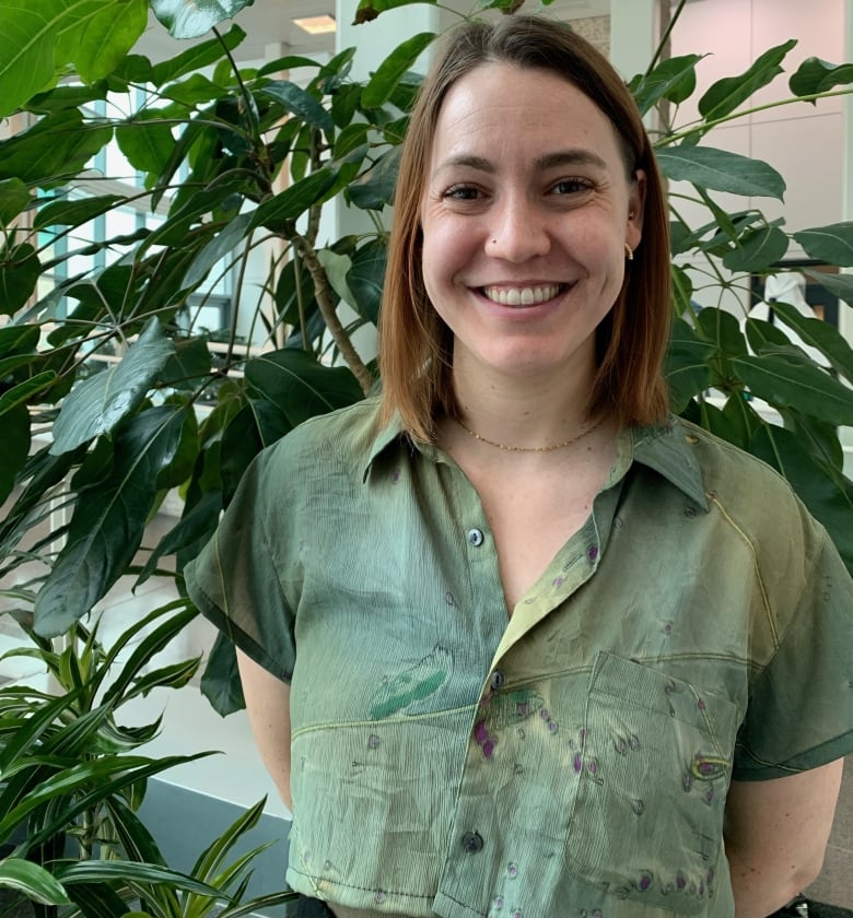 Heather Coatsworth smiles at the camera while surrounded by indoor plants. 