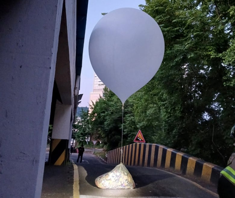 A balloon believed to have been sent by North Korea, carrying what could be trash, sits on a road in South Korea.