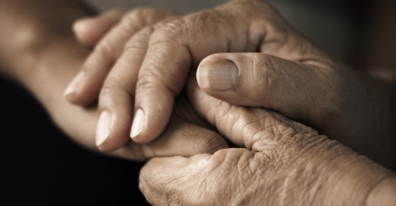 Two hands of elderly persons grasp together. 