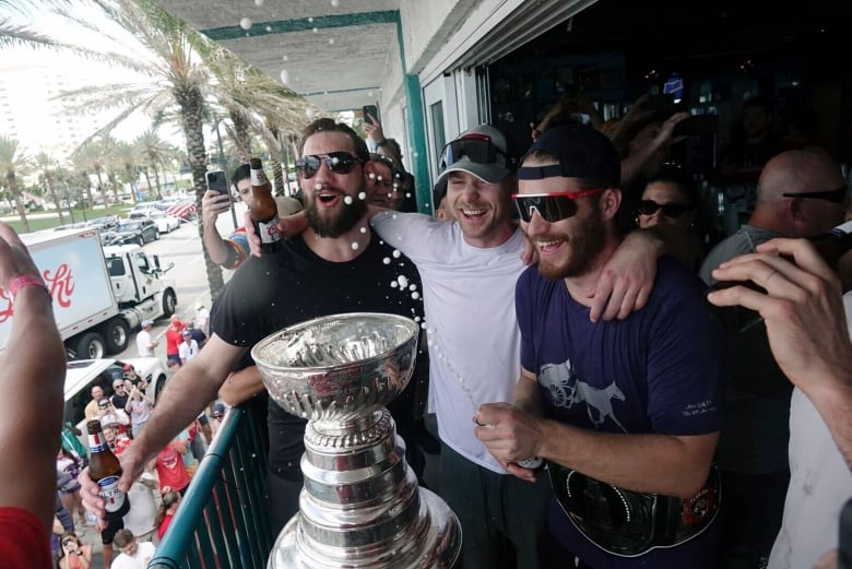 A  crowd of happy men  surround a trophy