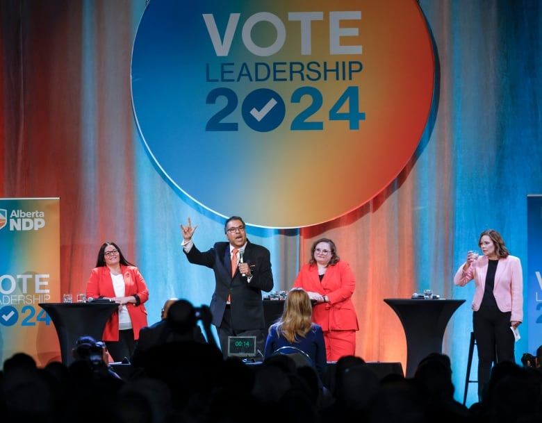 People stand on a stage in front of a colourful circle.