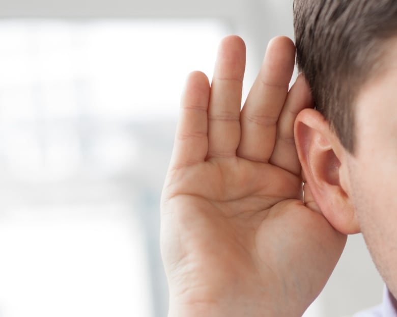 A stock image of a hand held out against an ear to increase hearing sensitivity.