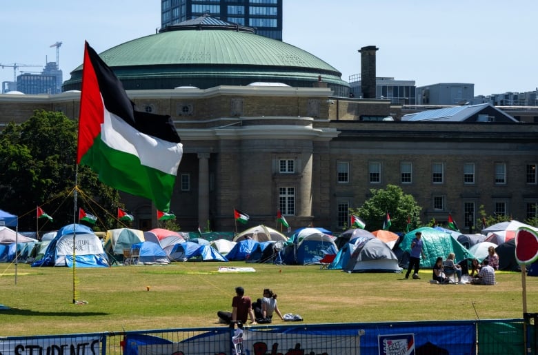 Tents and flags in front of a large building.