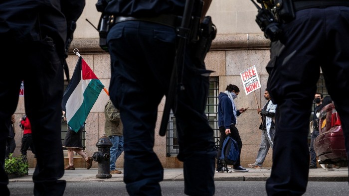 New York Police Officers keep an eye on protesters as they demonstrate outside Columbia University