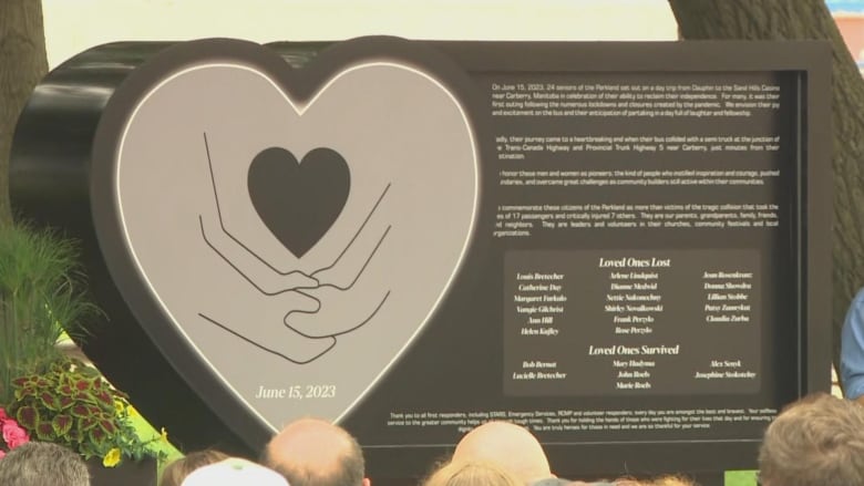 A monument is pictured. It has a heart shape on it with two people holding hands.