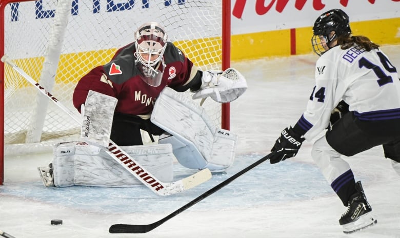 A female ice hockey player moves in to shoot on a female goaltender from close range during a game.