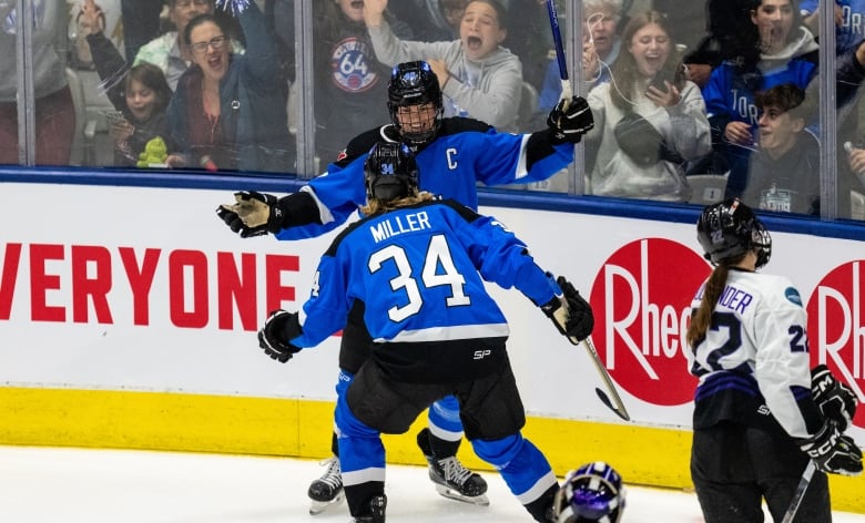 Two hockey players wearing blue Toronto jerseys celebrate on the ice.