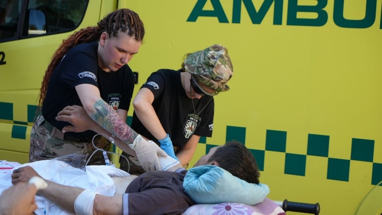 Tatiana Romaniuk, 33, and another paramedic help an inured soldier