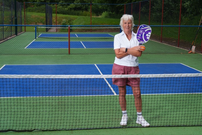 Woman wearing sports clothes standing at the net of a court holding a racket