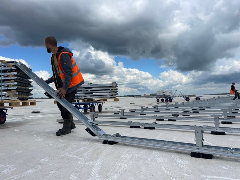 A worker installs rooftop solar panels in Dordrecht, The Netherlands