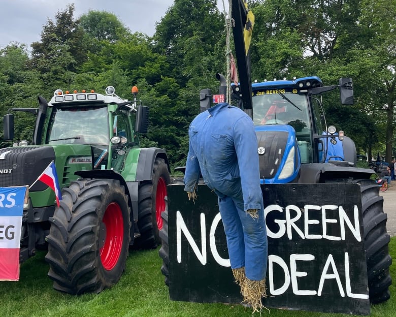 A tractor sits with a sign saying "no green deal" and a scarecrow on a noose, to imply that the green deal kills farmers.