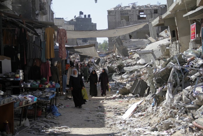 Palestinians walk near houses destroyed in the Israeli military offensive