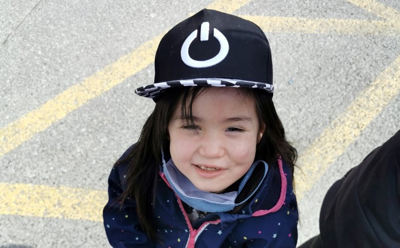 A girl with dark hair wearing a black hat.