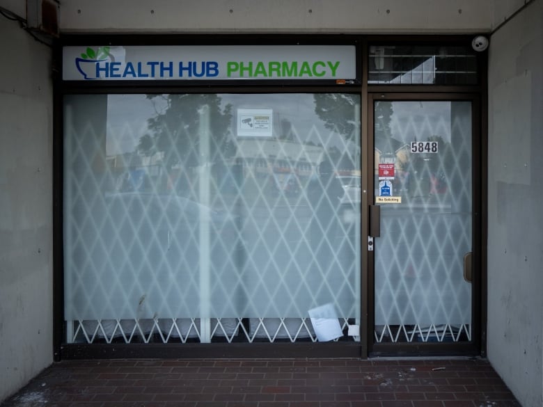 Shuttered pharmacy with a white cage over the front. 