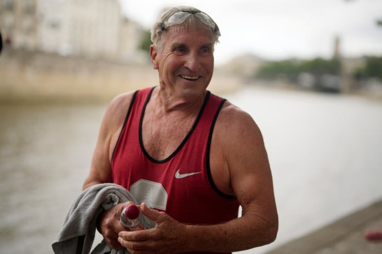 A man who has just gotten out of the water from swimming smiles.