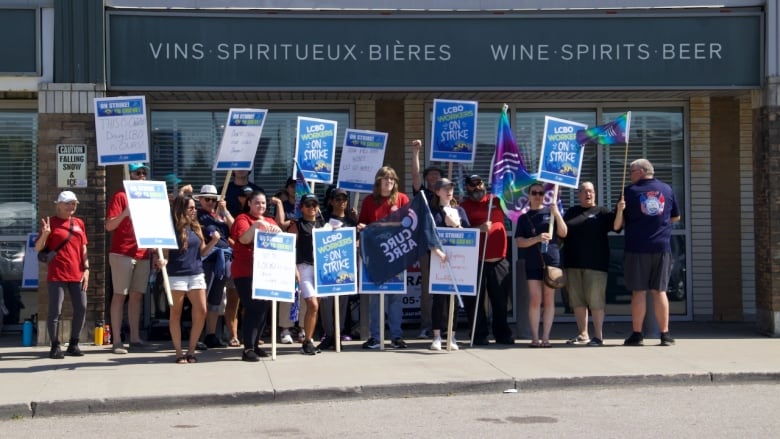 People holding signs protest outside a liquor store.