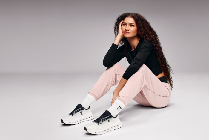 Zendaya sitting on the floor of a photographic studio wearing sportswear 