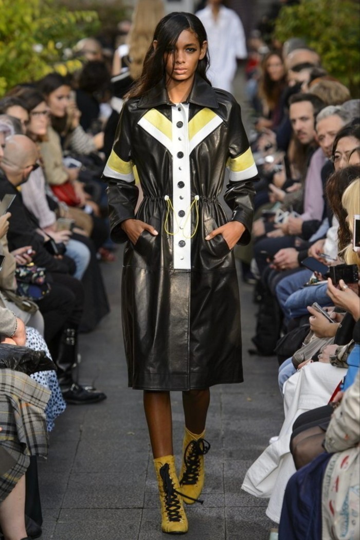 A model on the runway wears a black leather coat