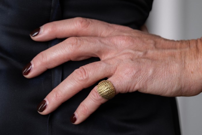 a bulbous golden ring placed on the pinky of a woman’s left hand