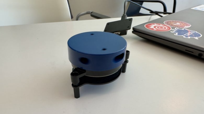 A circular sensor plugged into a laptop on a desk.