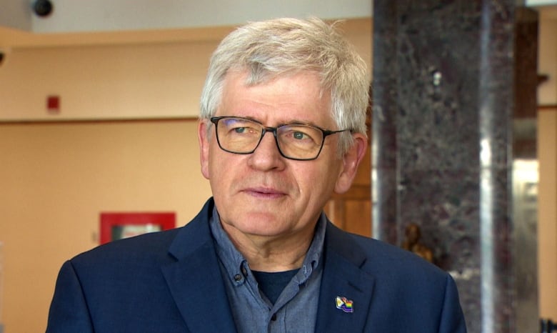 A man in a blue suit standing inside a lobby. 