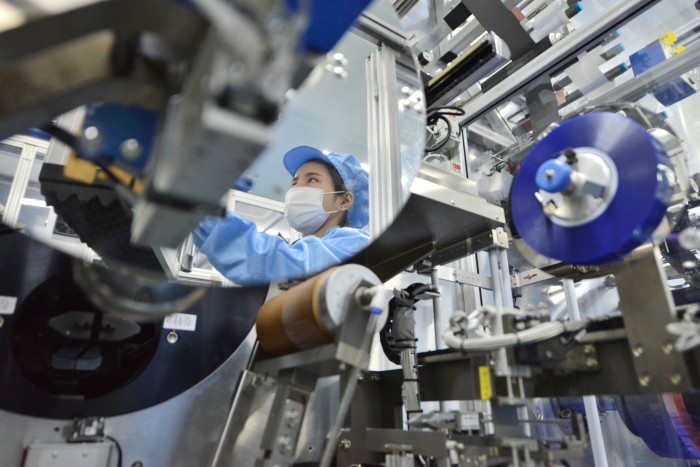 A factory worker is seen in a reflection at a lithium-ion battery production facility in China’s eastern Zhejiang province