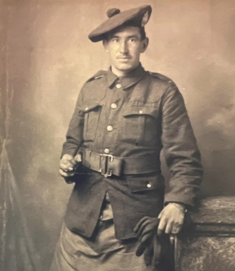 Man standing while wearing a Scottish army uniform, leans against a podium.