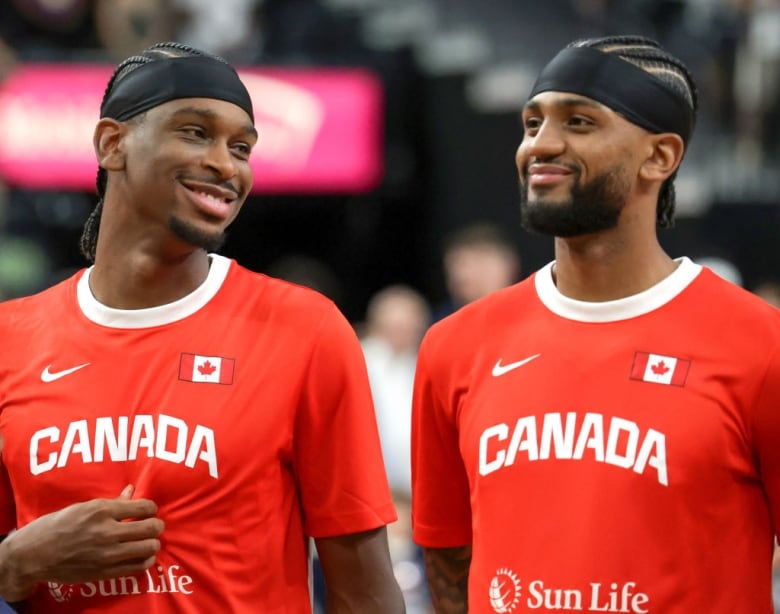 Two basketball players stand a smile.