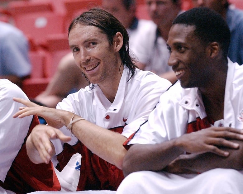 Two basketball players on the bench.