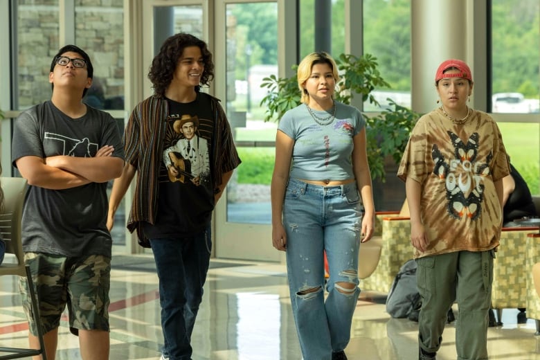 A group of teenagers walks through an indoor location. 