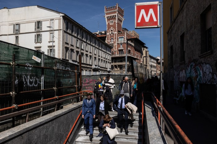 People walk down the stairs to the M2 Sant’Ambrogio metro station