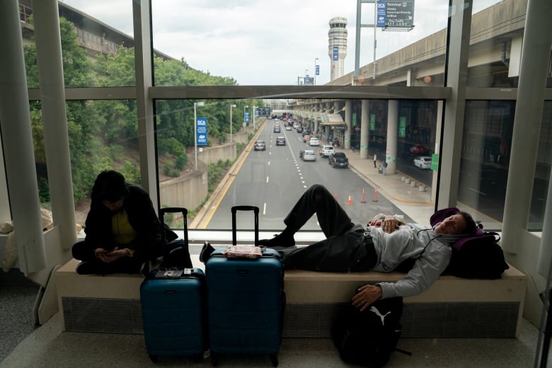 A man sleeps on a window ledge over a street