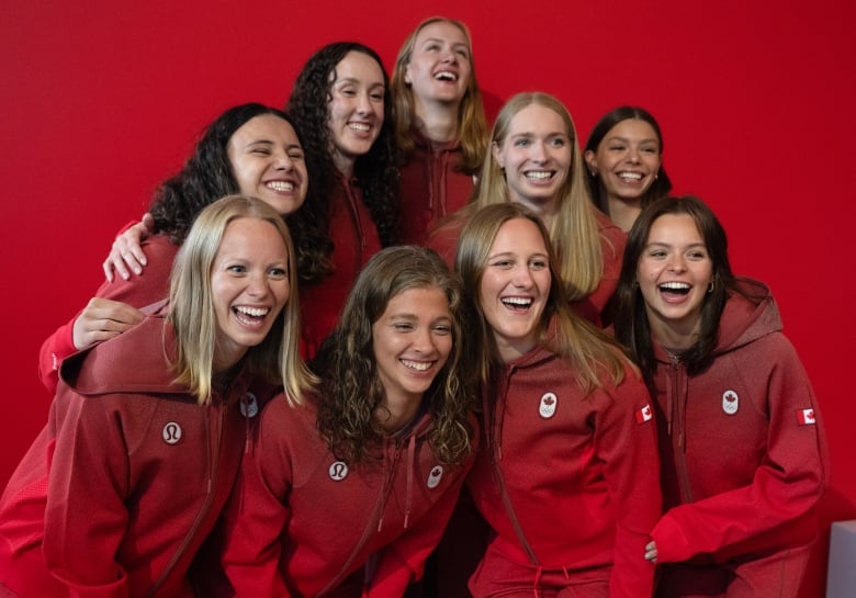 Nine women in red jumpsuits  smile