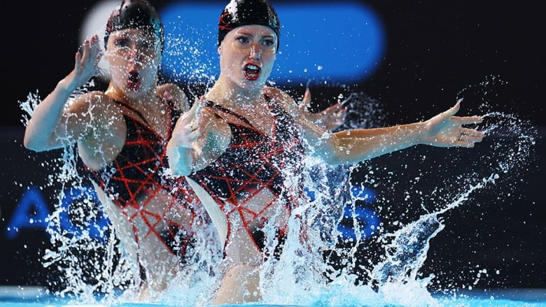 Two Canadian women's artistic swimmers, dressed in red and black swimsuits, perform their routine during the duet technical at a World Cup event on May 3, 2024 in Paris, France. 