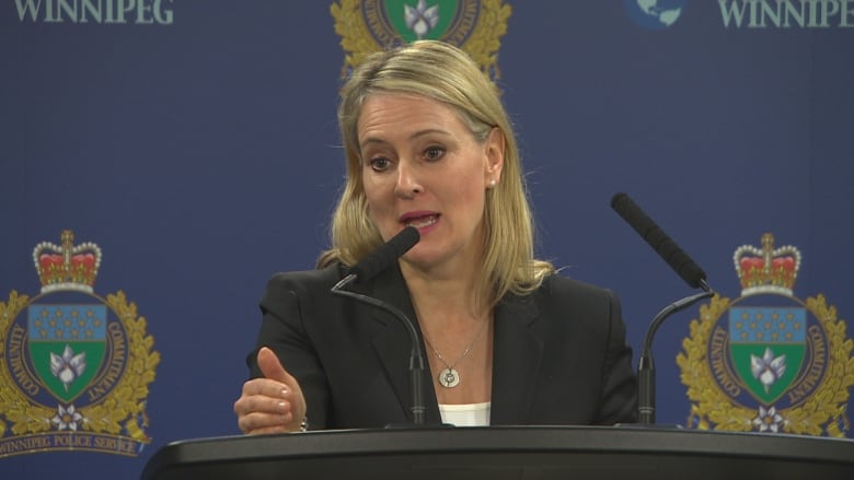 Woman speaking at a news conference in front of a microphone.