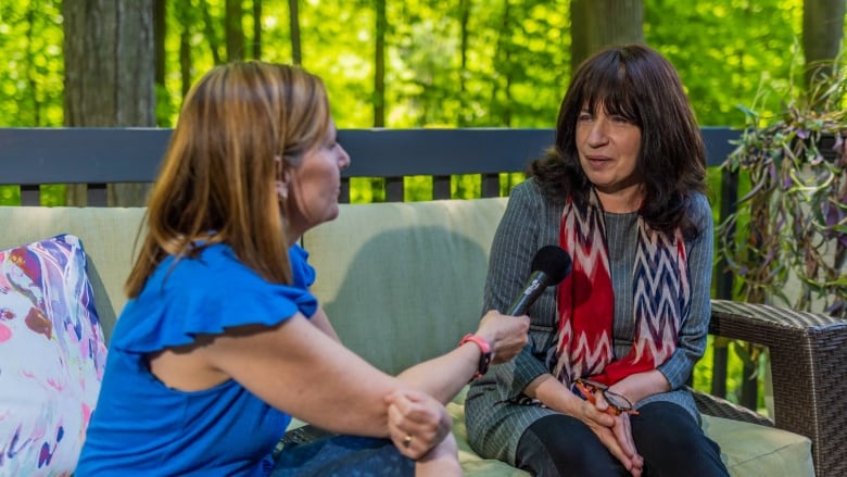 Woman holding a microphone, interviewing another woman