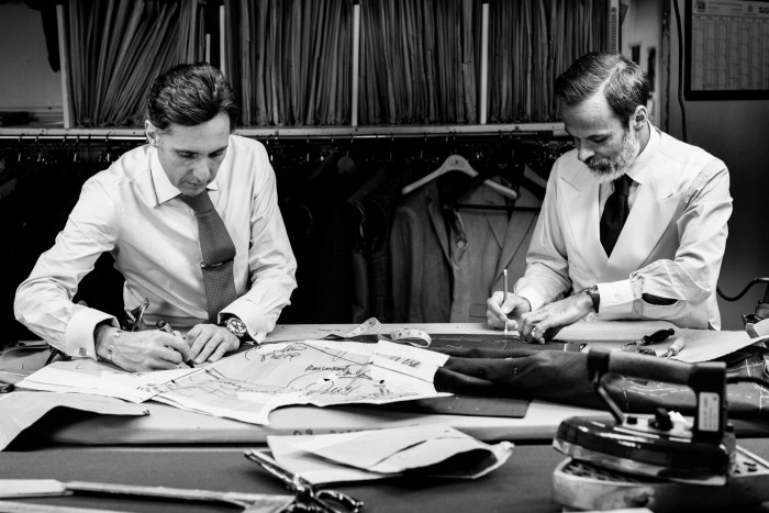 Black and white image of two tailors working at a table 