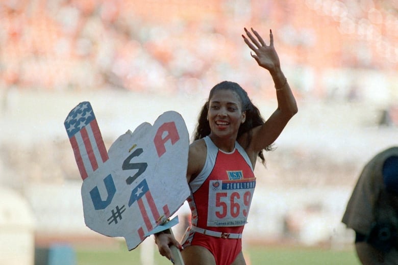 An athlete with long nails holds up a sign that says USA