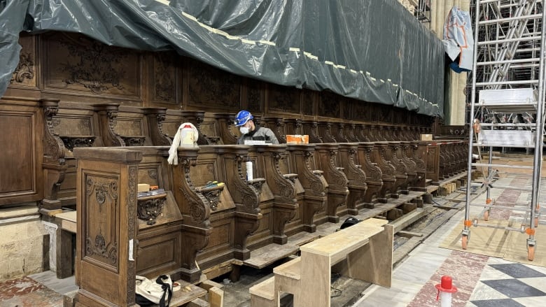 A man works on fixing choir stalls.