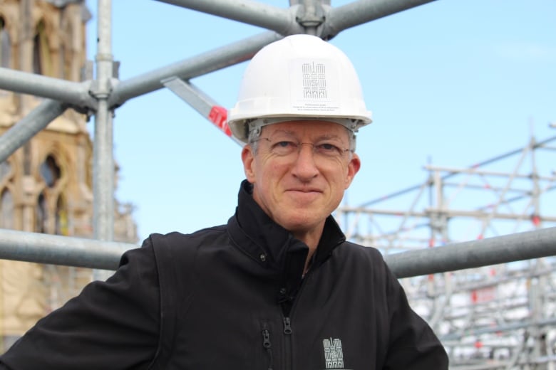 A man in a white hard hat and a black jacket.