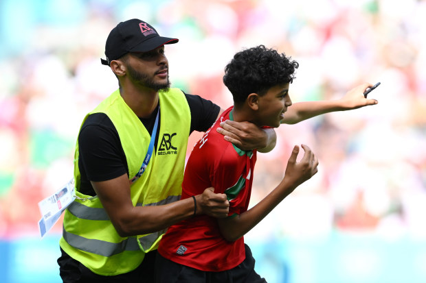 A pitch invader is apprehended by a steward.