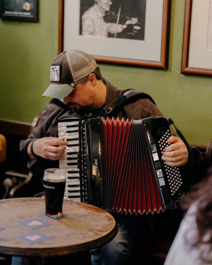 A man in a baseball cap playing an accordeon at Sandy Bell’s