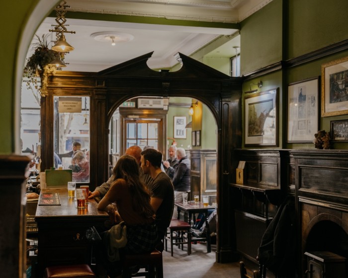 A dark-wood arch and dark-wood panelling below green-painted walls in Sandy Bell’s