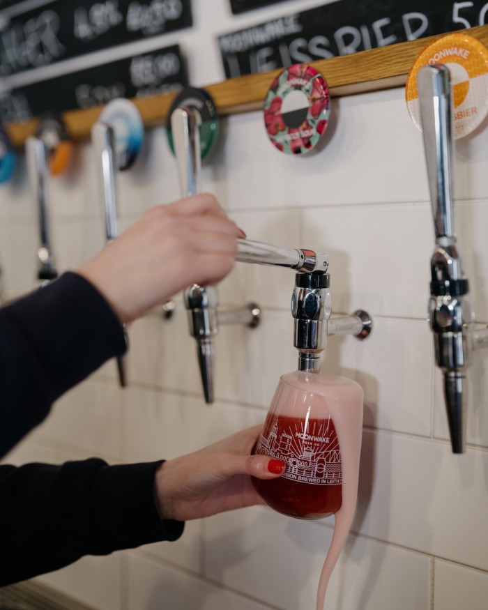 A woman’s hands pulling a pint of hibiscus sour at Moonwake