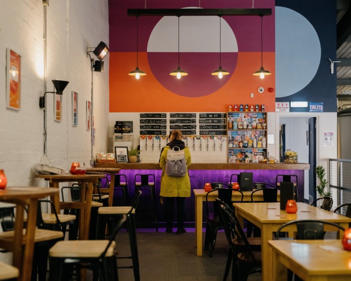 Whitewashed brick walls and large orange and blue artworks depicting large circles hanging from the ceiling in Moonwake’s bar