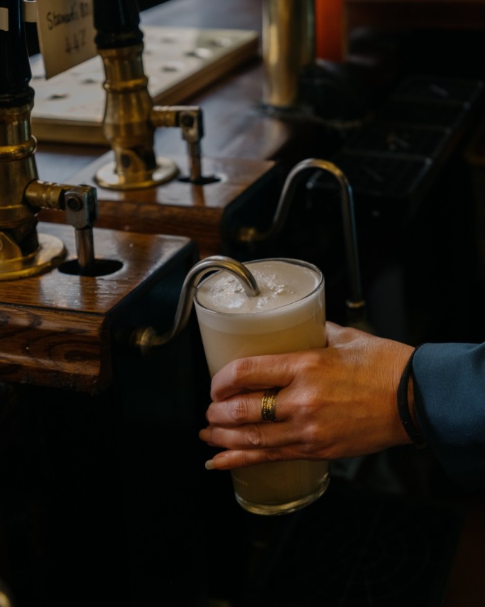 A woman’s hand pulling a pint of beer in The ‘Oxford’ 